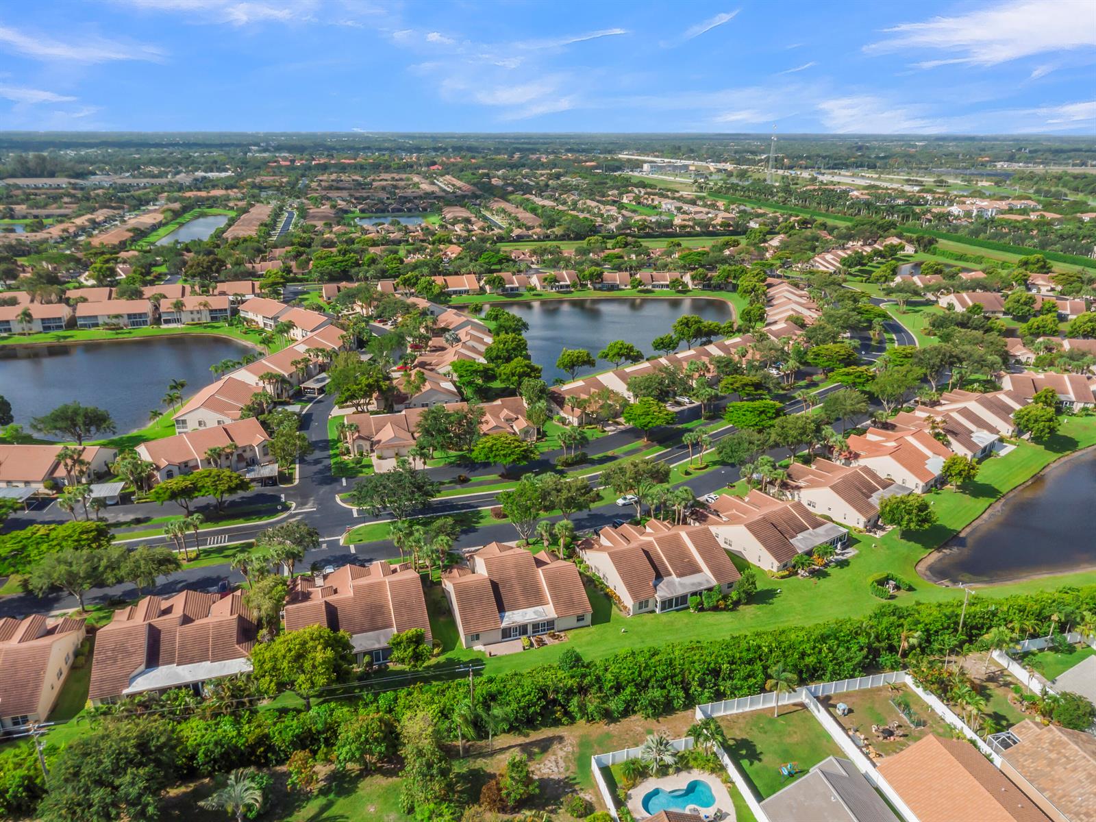 An aerial view of a residential neighborhood featuring townhouses, lakes, and lush green landscaping — 7773 Silver Lake Drive, Delray Beach FL 33446, DELRAY BEACH, FL