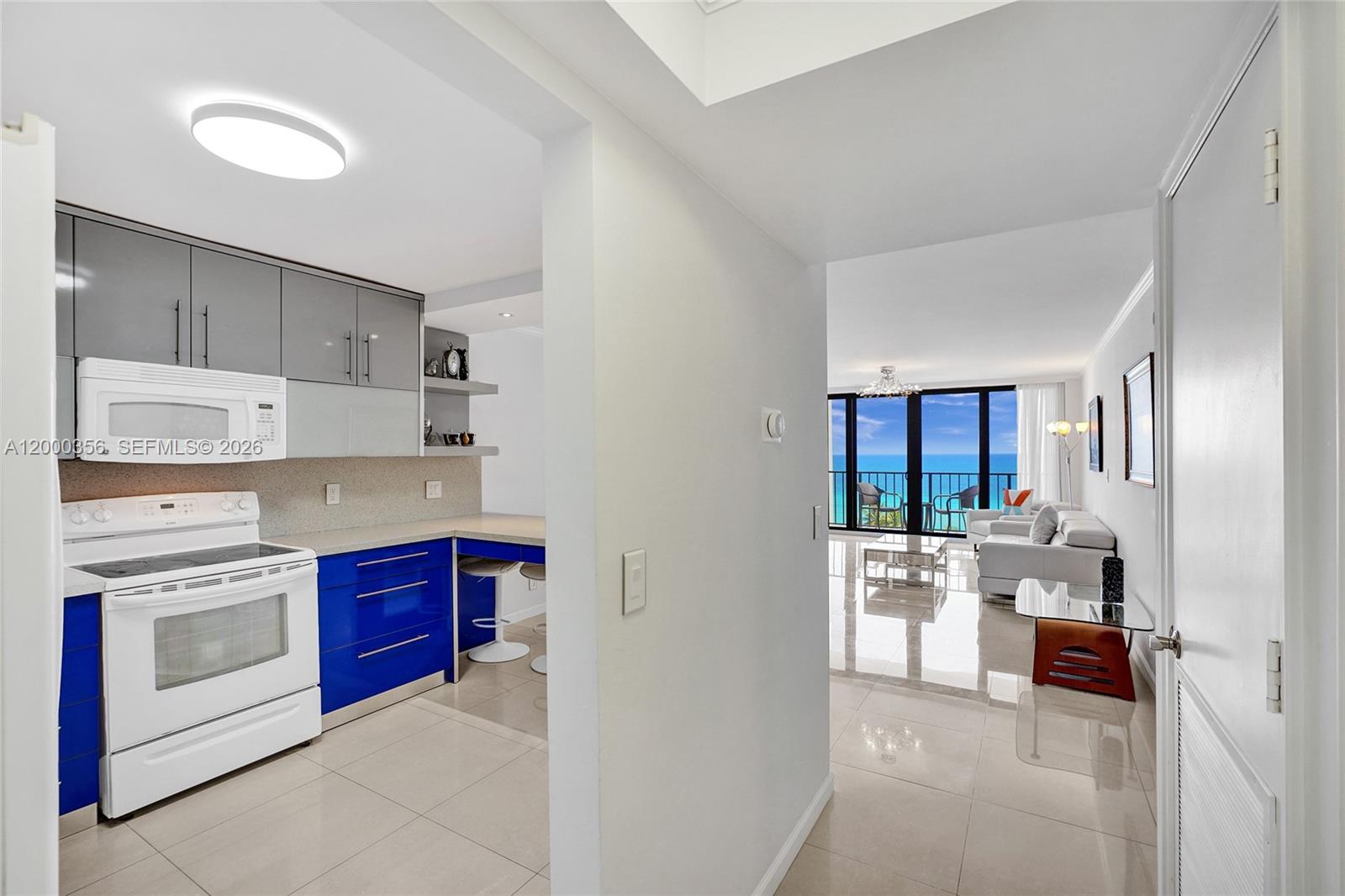 A kitchen with blue cabinets and white appliances opens into a living area with ocean views — 2401 S Ocean Dr, Hollywood FL 33019, HOLLYWOOD, FL