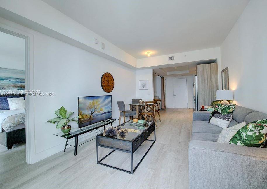 A living room features a gray sofa, a glass coffee table, and a television — 121 NE 34th St # 1603, Miami FL 33137, MIAMI, FL