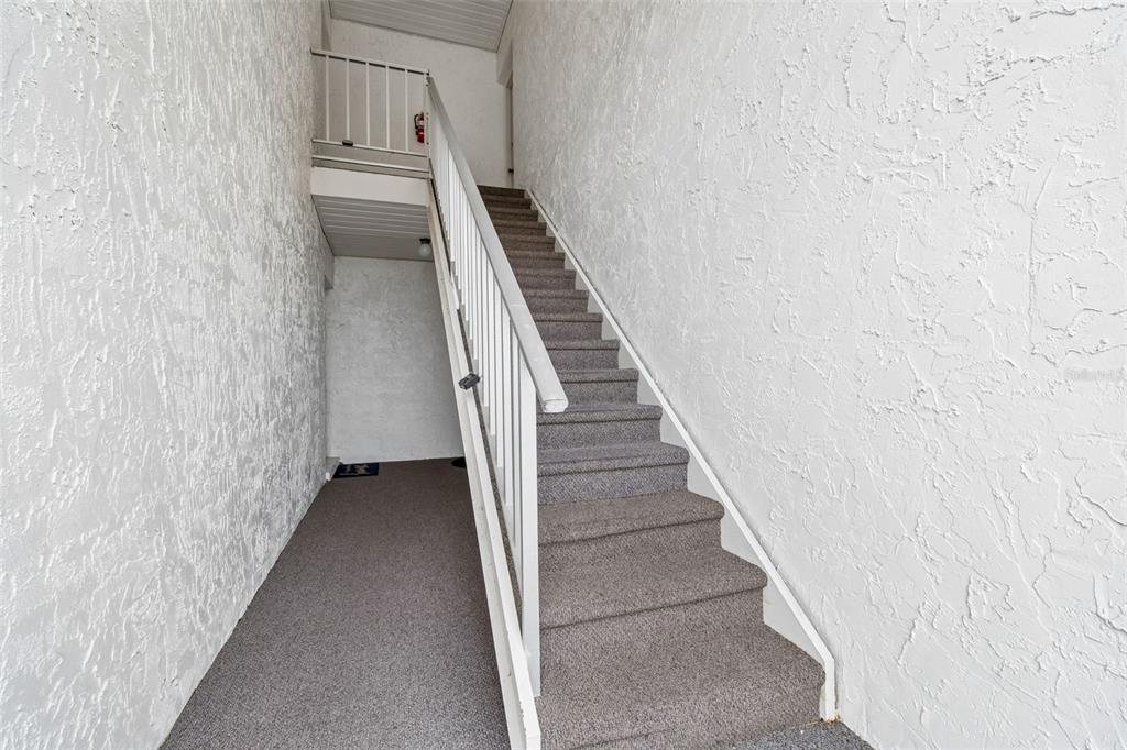 A staircase with gray carpet and white railings leads to an upper landing — 239 S MCMULLEN BOOTH ROAD UNIT 37, CLEARWATER, FL