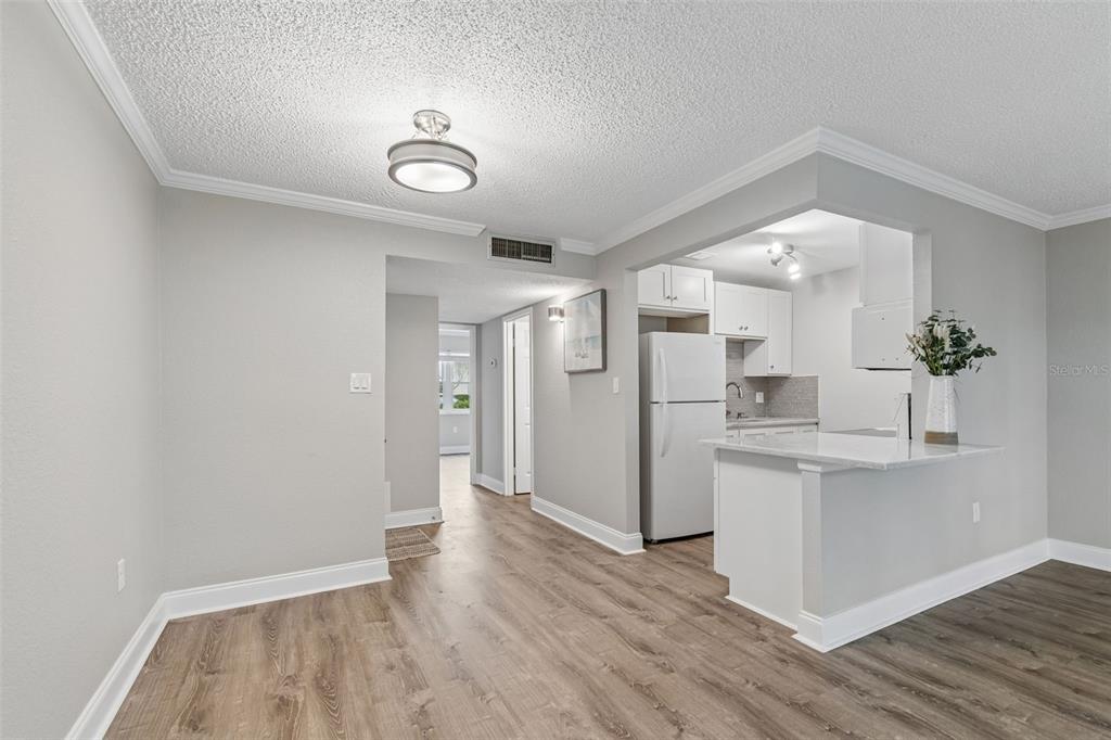 A dining area with wood-look flooring connects to a kitchen featuring white cabinets and counters — 239 S MCMULLEN BOOTH ROAD UNIT 37, CLEARWATER, FL