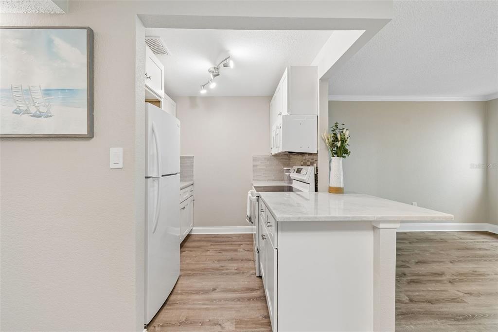 A kitchen features white cabinets, a white refrigerator, and a marble-topped breakfast bar — 239 S MCMULLEN BOOTH ROAD UNIT 37, CLEARWATER, FL