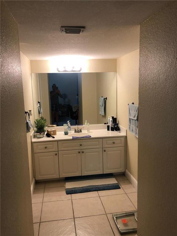 A bathroom features a white vanity with a single sink, a large mirror, and tiled flooring — 10411 N Kendall Drive # B203, Miami FL 33176, MIAMI, FL