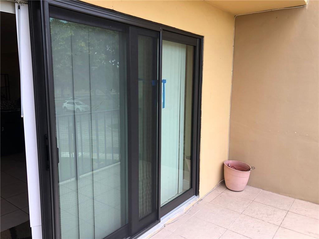 A sliding glass door with a screen leads to a tiled balcony with a planter — 10411 N Kendall Drive # B203, Miami FL 33176, MIAMI, FL
