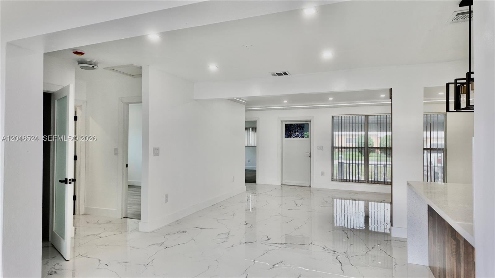A bright, open-concept living area features white marble-patterned tile floors and recessed ceiling lighting — 7721 Granada Blvd, Miramar FL 33023, MIRAMAR, FL
