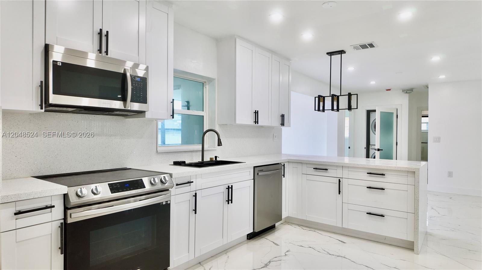 A modern kitchen features white cabinets, stainless steel appliances, and white marble-patterned tile flooring — 7721 Granada Blvd, Miramar FL 33023, MIRAMAR, FL