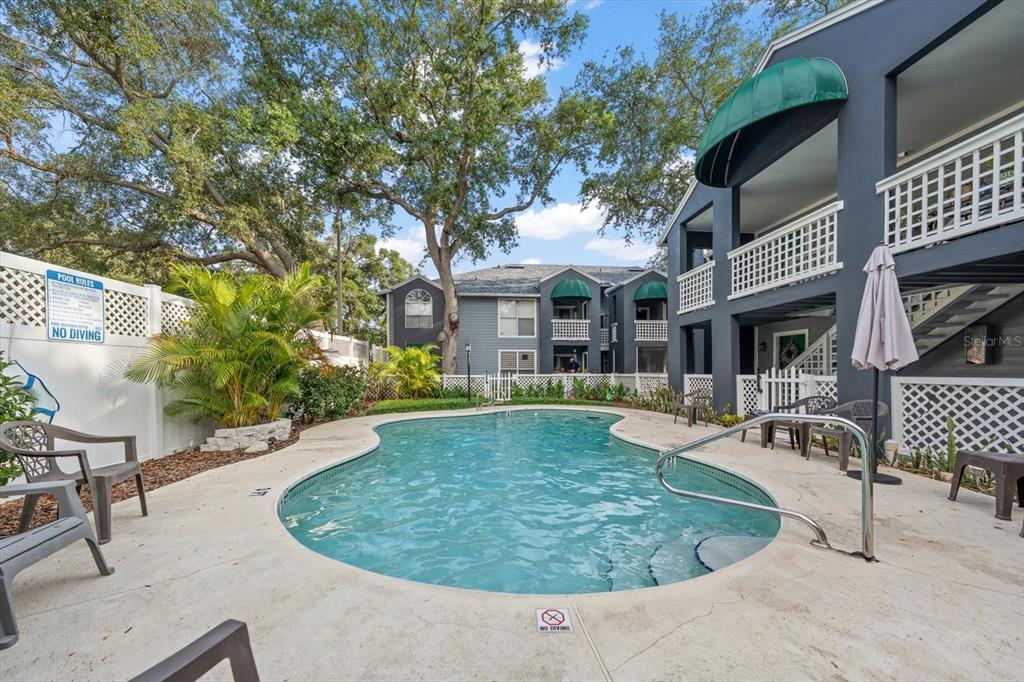A swimming pool sits in the courtyard of a multi-story apartment building with green awnings — 606 S ALBANY AVENUE UNIT 5, TAMPA, FL
