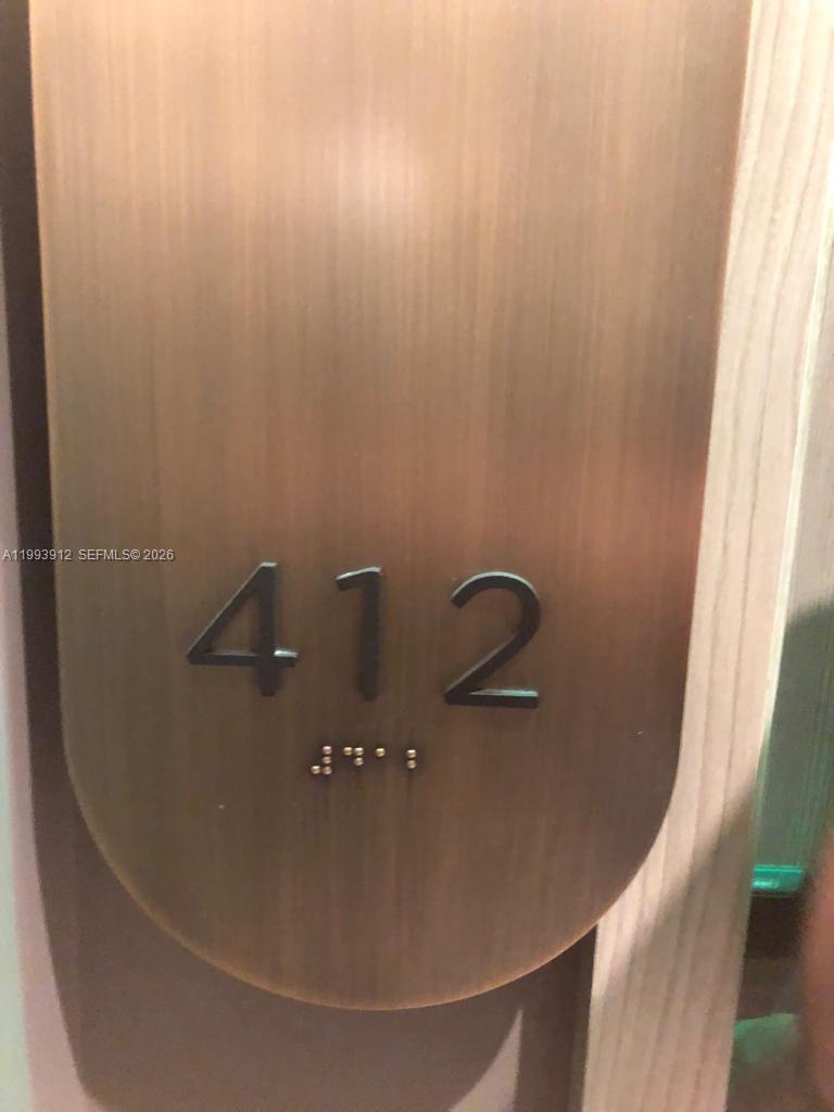 A close-up view of a metallic door sign displaying the number 412 with braille — 801 S Miami Ave # 412, Miami FL 33131, MIAMI, FL