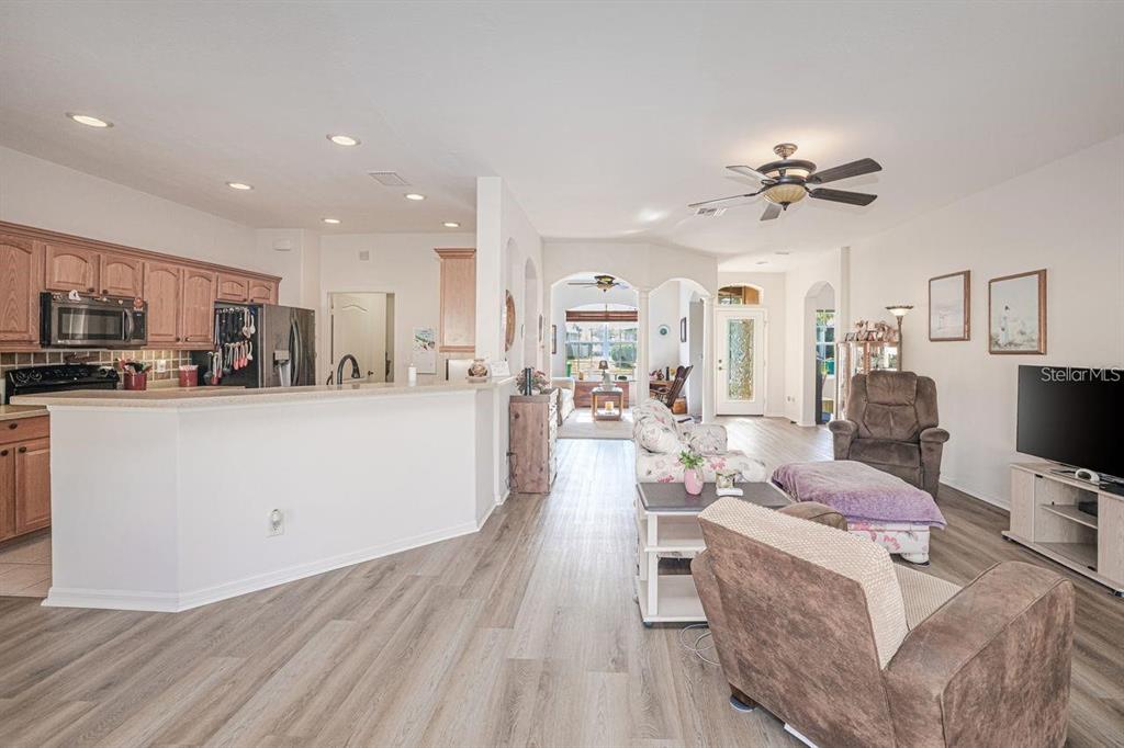 An open-concept living room and kitchen with light wood-look flooring and a ceiling fan — 2860 SUNCOAST LAKES BOULEVARD, PORT CHARLOTTE, FL