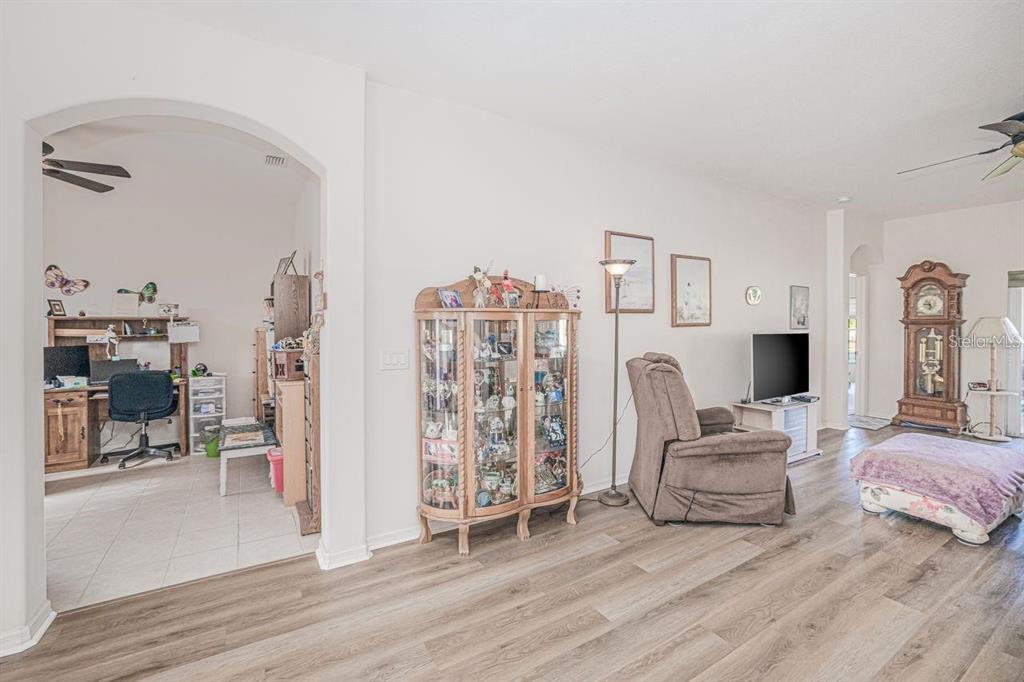 A living room with wood-look flooring, a curio cabinet, a recliner, and a desk area — 2860 SUNCOAST LAKES BOULEVARD, PORT CHARLOTTE, FL