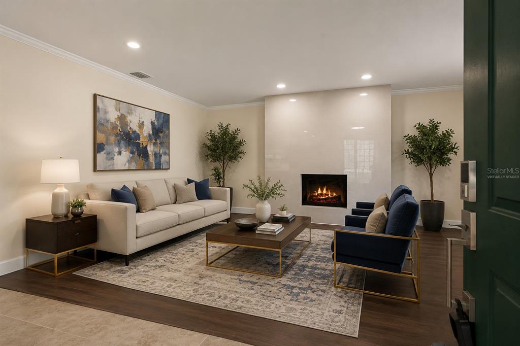 A living room features a fireplace, a beige sofa, two blue chairs, and an area rug — 4247 HELENA STREET NE, ST PETERSBURG, FL
