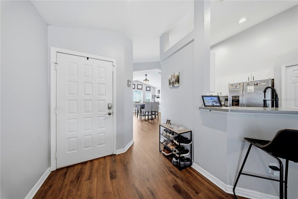 An entryway with wood-look flooring leads to a dining area and a kitchen with bar seating — 6618 SUMMER COVE DRIVE, RIVERVIEW, FL