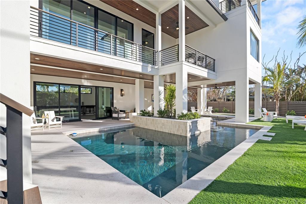 A modern two-story house features a swimming pool with a central planter and covered patio — 7007 POINT OF ROCKS ROAD, SARASOTA, FL