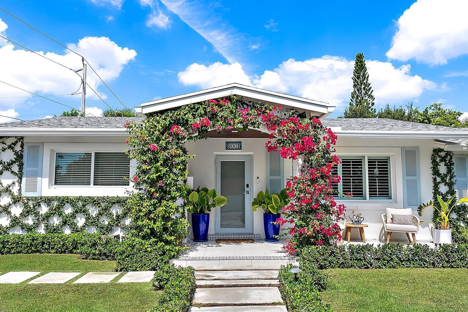 A white house features a front entrance framed by a vibrant pink bougainvillea archway — 8001 Arlington Place, West Palm Beach FL 33405, WEST PALM BEACH, FL