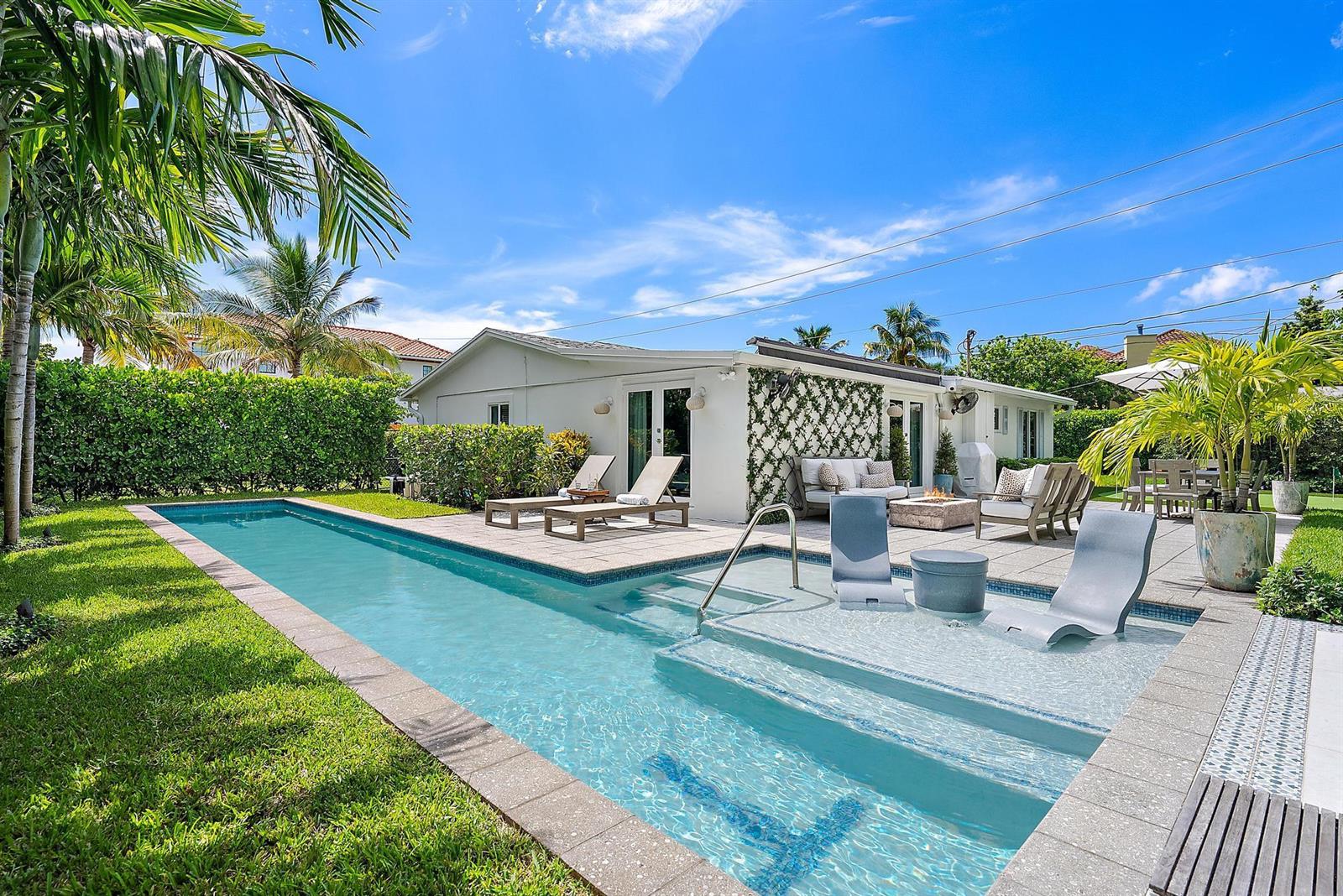 A backyard features a rectangular swimming pool with a tanning ledge and a stone patio — 8001 Arlington Place, West Palm Beach FL 33405, WEST PALM BEACH, FL