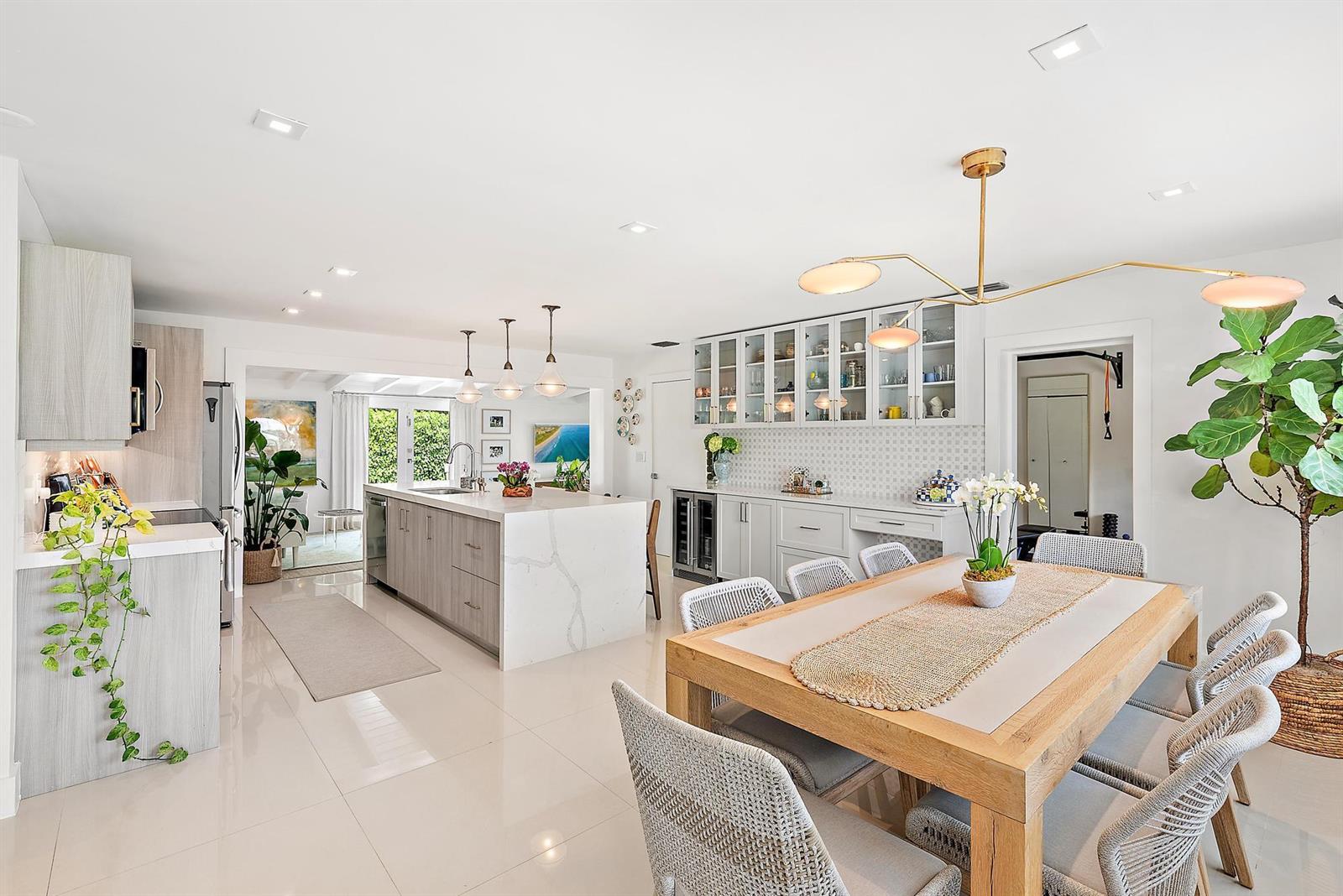 A bright, open-concept kitchen and dining area featuring a marble island and wooden table — 8001 Arlington Place, West Palm Beach FL 33405, WEST PALM BEACH, FL