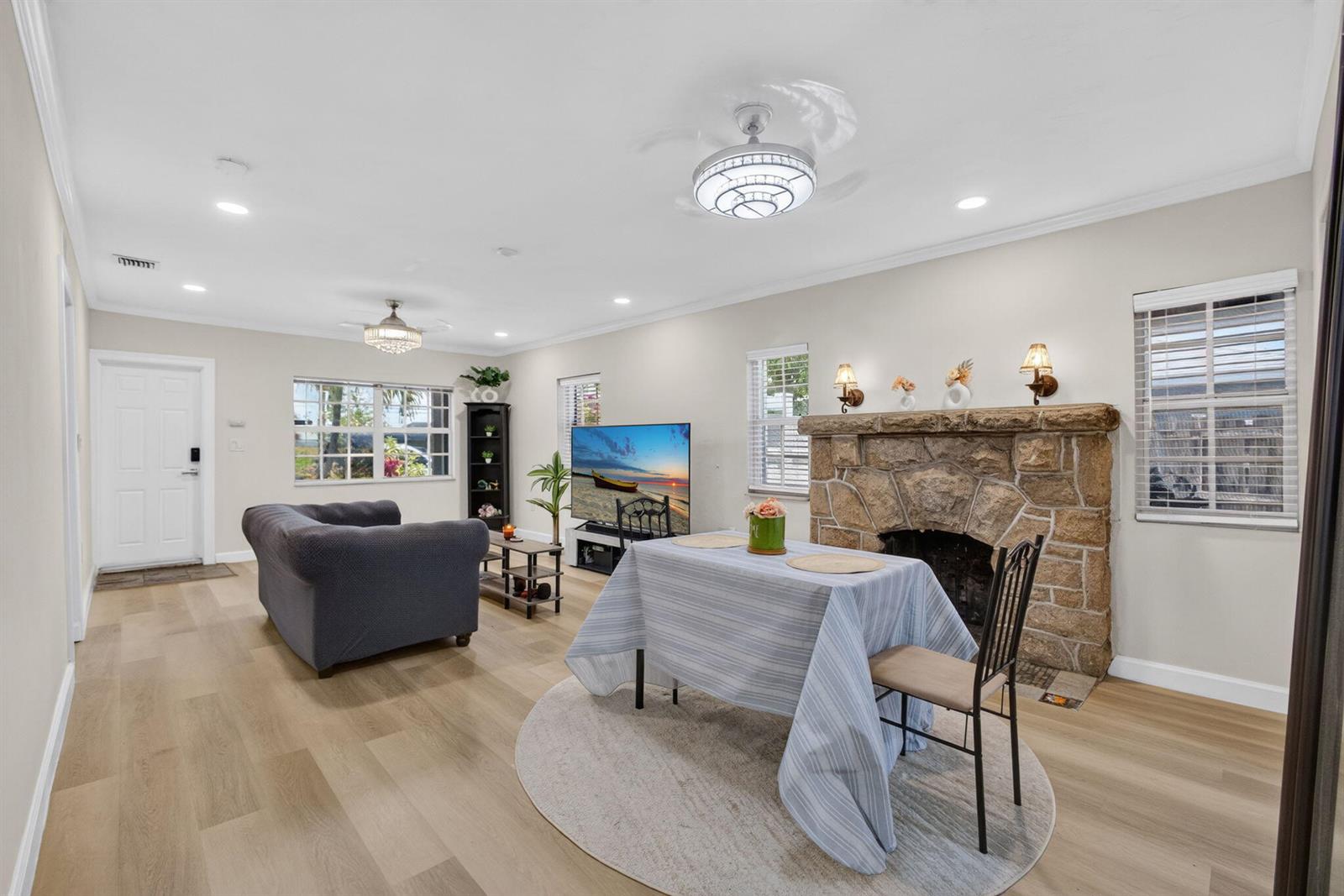 A living and dining area features light wood floors, a stone fireplace, and ceiling fans — 1314 N J Street, FL 33460, FL