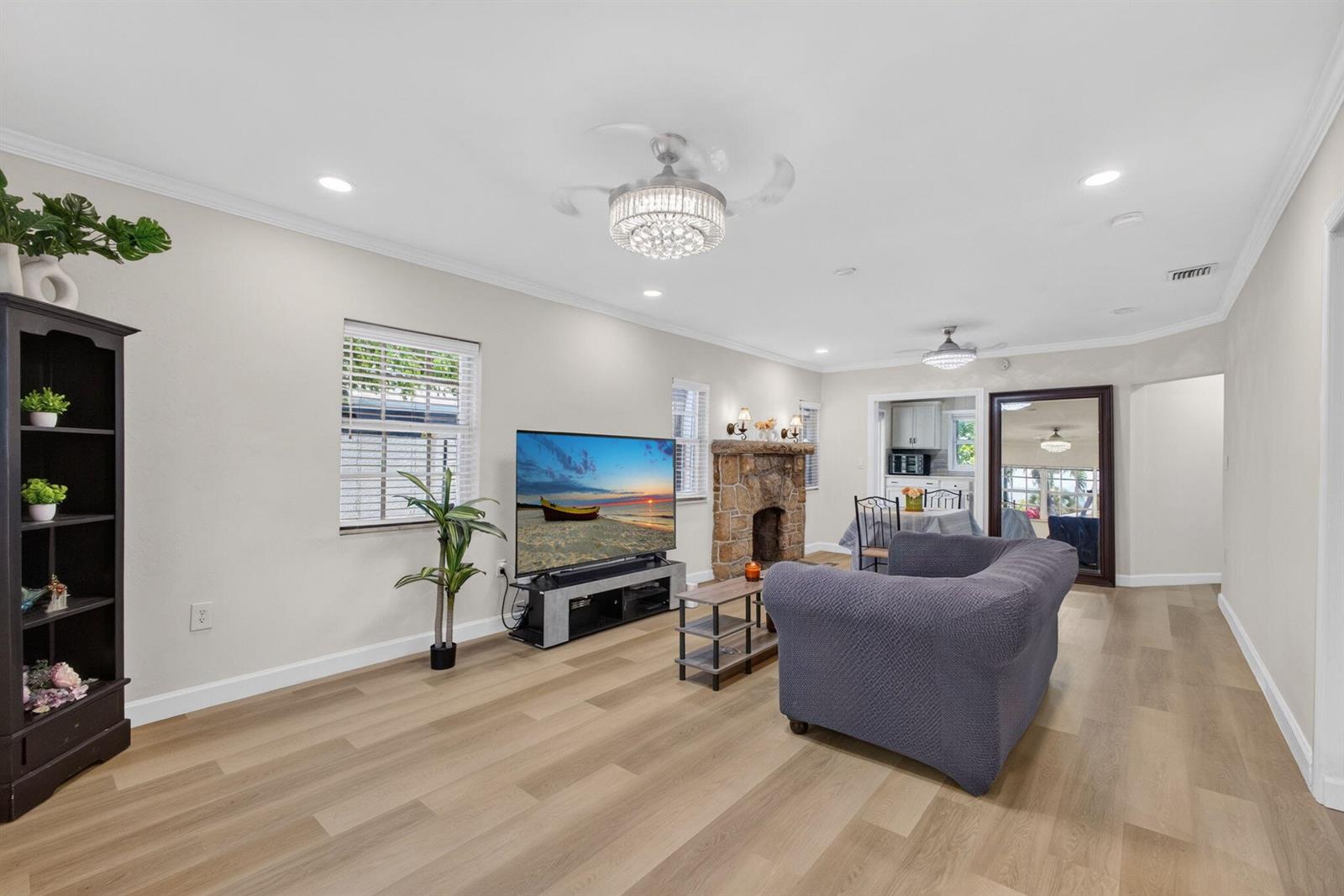A living room features light wood flooring, a stone fireplace, a television, and a sofa — 1314 N J Street, FL 33460, FL