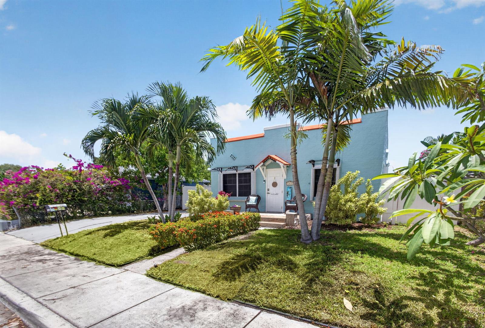 A light blue house with a white door, palm trees, and landscaping under a blue sky — 1314 N J Street, FL 33460, FL