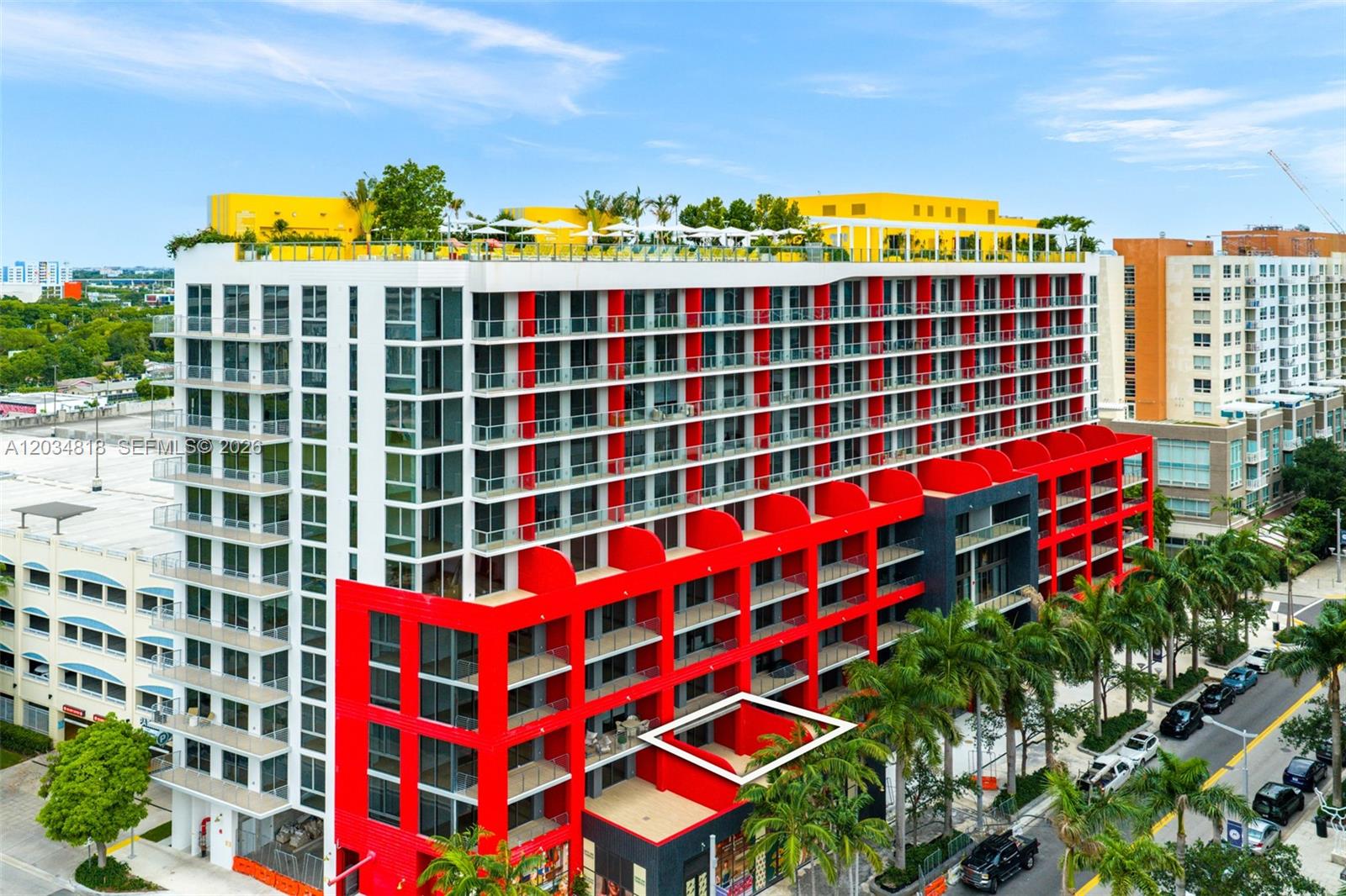 An exterior view of a modern apartment building featuring red accents and a rooftop pool — 90 NE 32 St # 203, Miami FL 33127, MIAMI, FL