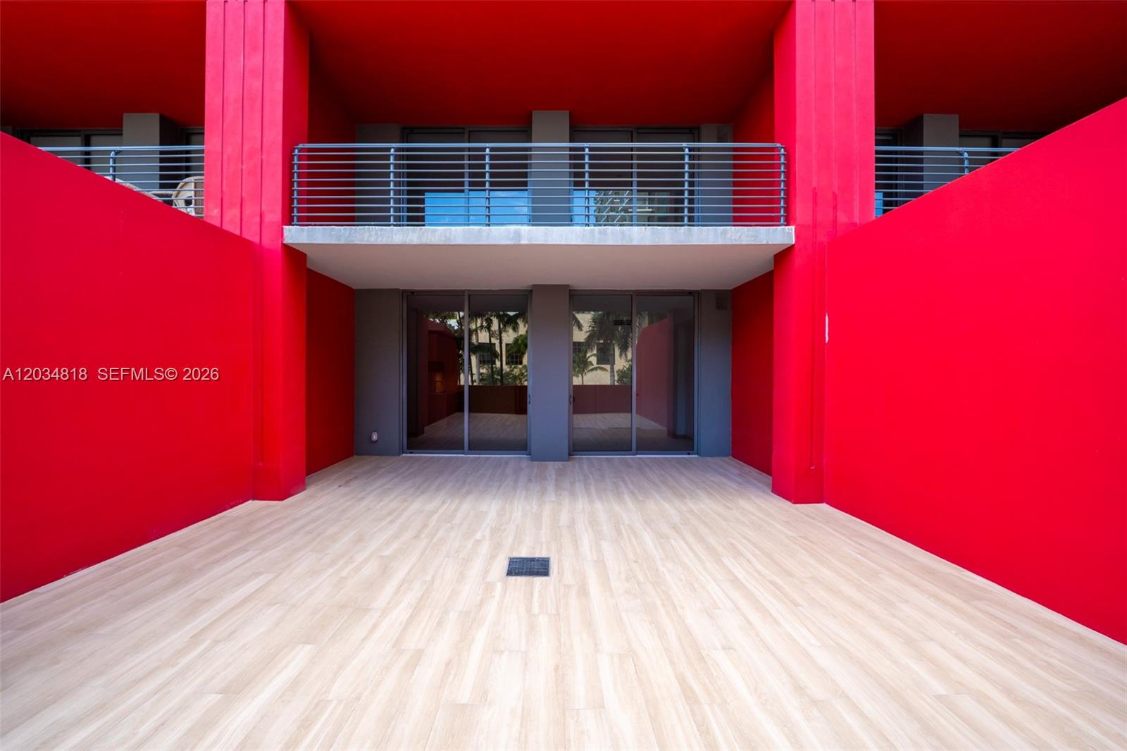 A bright red outdoor patio features light wood-look tile flooring and a second-story balcony — 90 NE 32 St # 203, Miami FL 33127, MIAMI, FL