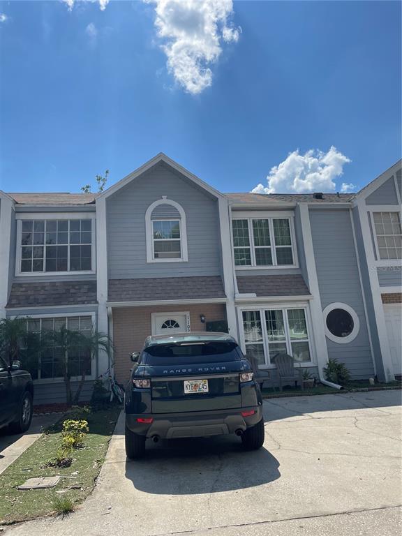 A two-story townhouse with gray siding and a dark SUV parked in the driveway — 11020 YORKSHIRE RIDGE COURT, ORLANDO, FL