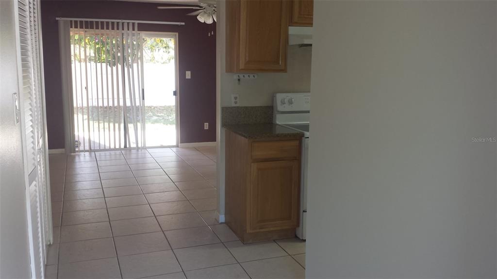 A kitchen with wood cabinets and tile flooring leads to a living area with sliders — 11020 YORKSHIRE RIDGE COURT, ORLANDO, FL