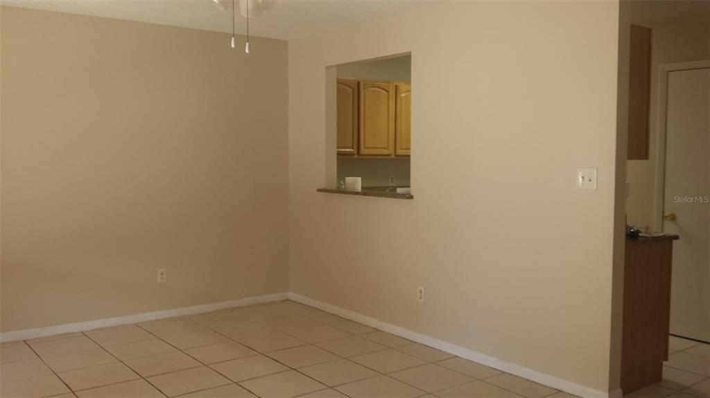 A dining area with beige walls, tile flooring, and a pass-through window to the kitchen — 11020 YORKSHIRE RIDGE COURT, ORLANDO, FL
