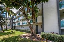 A low-angle view of a multi-story apartment building exterior with palm trees and landscaping — 8445 Springtree Dr # 202A, Sunrise FL 33351, SUNRISE, FL