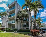 A multi-story residential building features balconies with glass railings surrounded by palm trees — 8445 Springtree Dr # 202A, Sunrise FL 33351, SUNRISE, FL