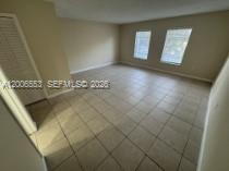 An empty room features light-colored tile flooring, beige walls, and two windows — 8445 Springtree Dr # 202A, Sunrise FL 33351, SUNRISE, FL
