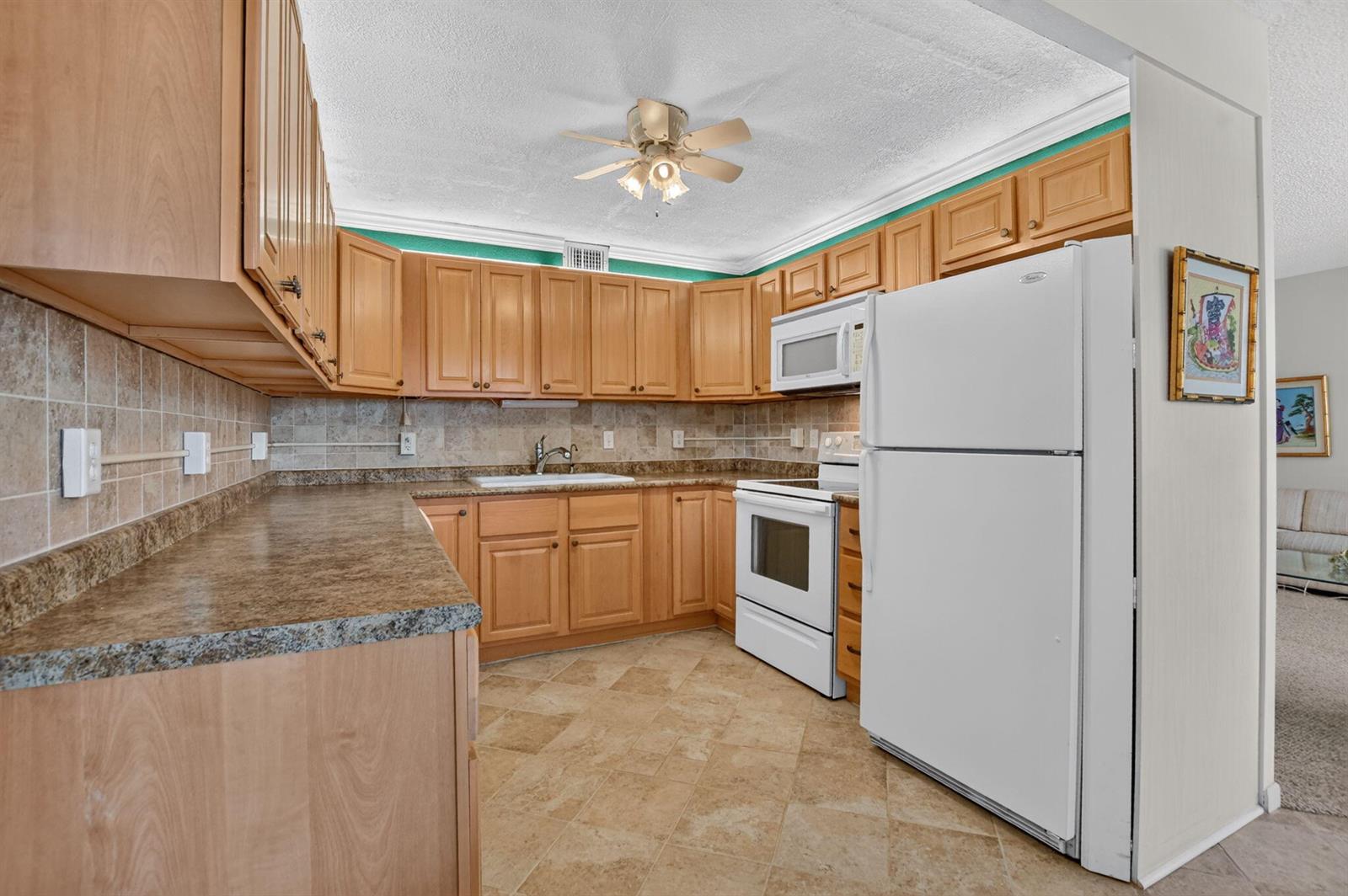 A kitchen features light wood cabinets, brown laminate countertops, white appliances, and tiled flooring — 2049 Ventnor O Crescent # 2049, Deerfield Beach FL 33442, DEERFIELD BEACH, FL