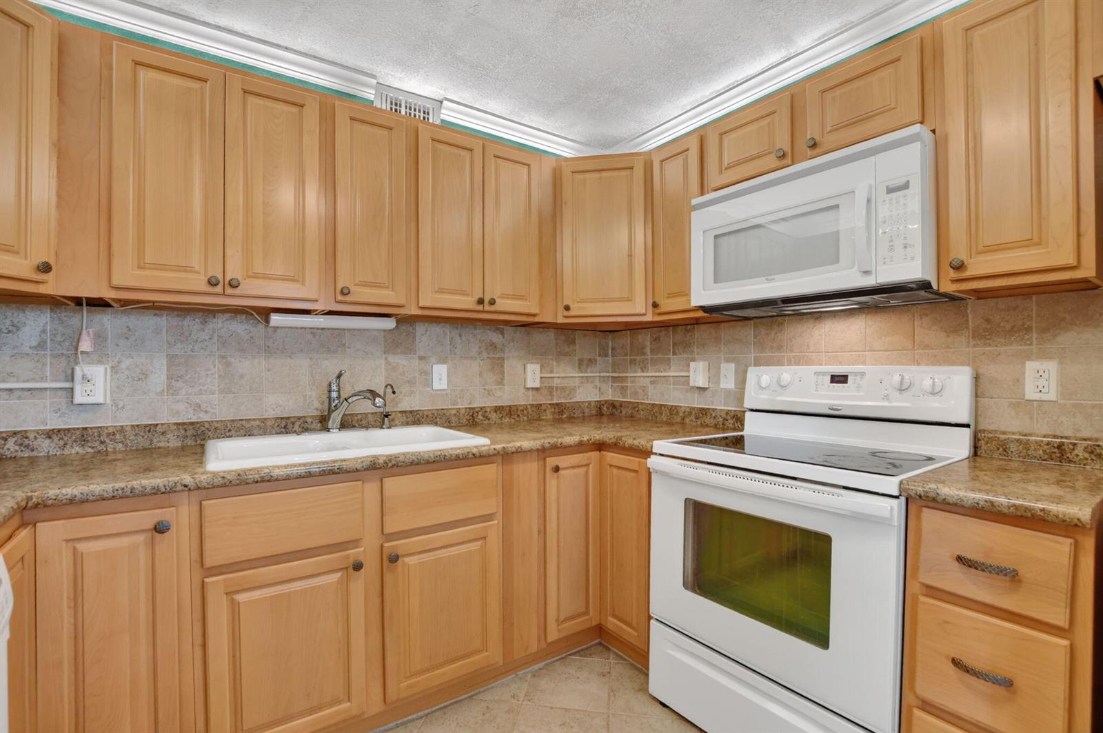 A kitchen with light wood cabinets, white appliances, granite countertops, and a tiled backsplash — 2049 Ventnor O Crescent # 2049, Deerfield Beach FL 33442, DEERFIELD BEACH, FL