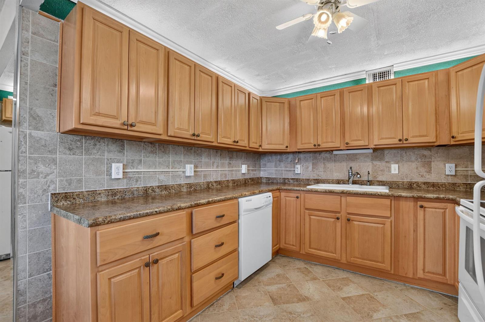 A kitchen featuring light wood cabinets, granite countertops, tile backsplash, and tile flooring — 2049 Ventnor O Crescent # 2049, Deerfield Beach FL 33442, DEERFIELD BEACH, FL