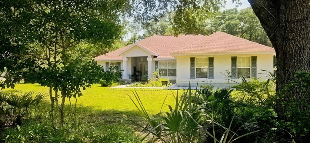 A single-story house with a light-colored exterior and a red roof sits on a lawn — 19965 NW 257TH TERRACE, HIGH SPRINGS, FL