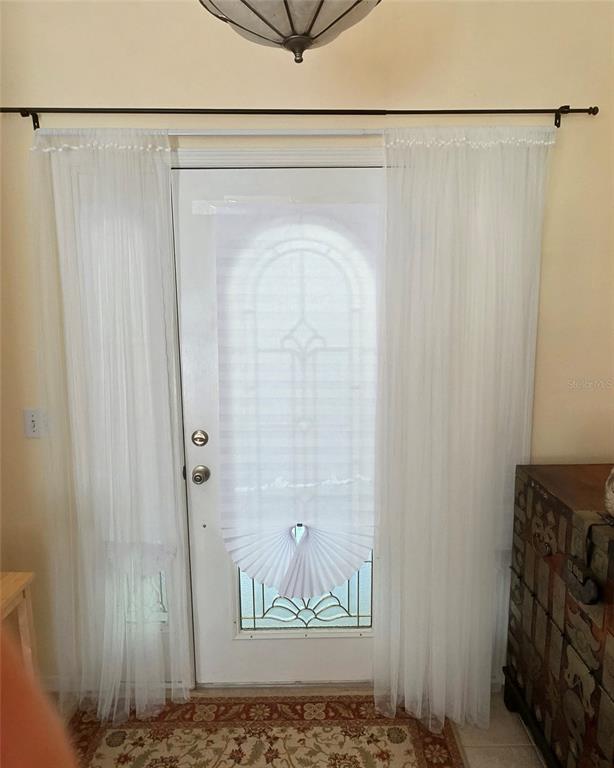 A white door with a pleated shade and sheer curtains stands in an entryway — 19965 NW 257TH TERRACE, HIGH SPRINGS, FL
