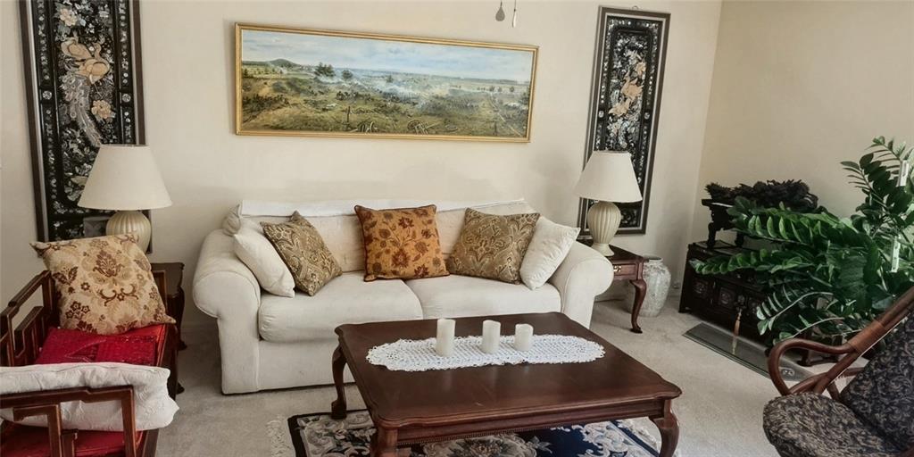 A living room features a white sofa, a wooden coffee table, and decorative wall art — 19965 NW 257TH TERRACE, HIGH SPRINGS, FL