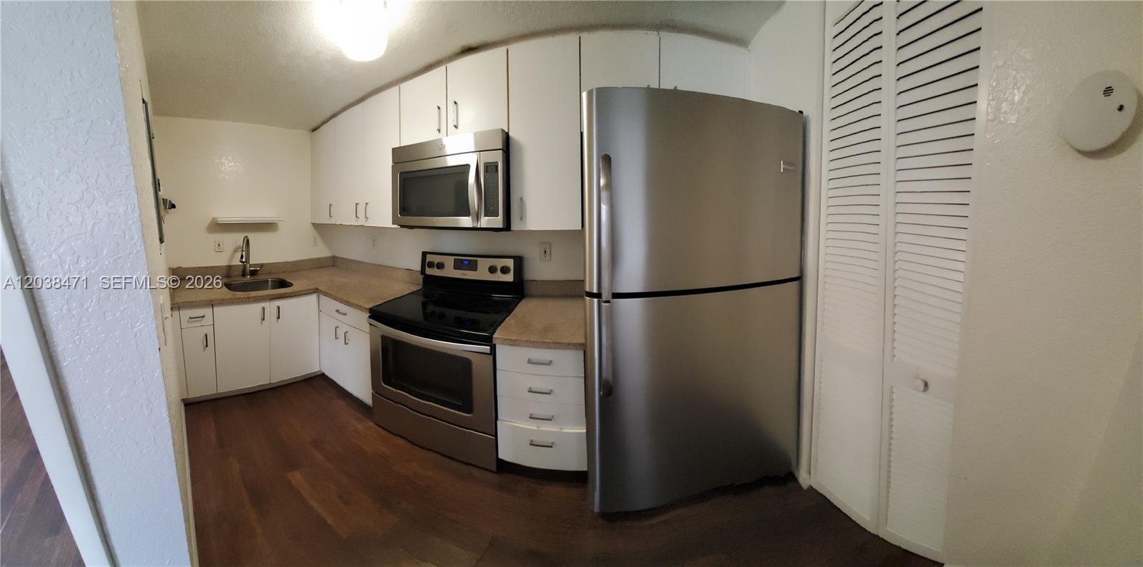 A kitchen features white cabinets, stainless steel appliances, and wood-look flooring — 300 NW 84th Ter # 300, Miami FL 33150, MIAMI, FL
