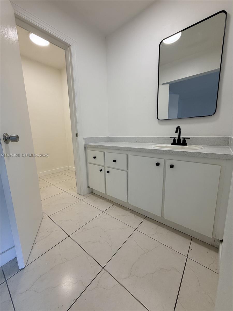 A bathroom features a white vanity with a black faucet, a mirror, and tiled flooring — 1525 NW 19th Ter # 15, Miami FL 33125, MIAMI, FL