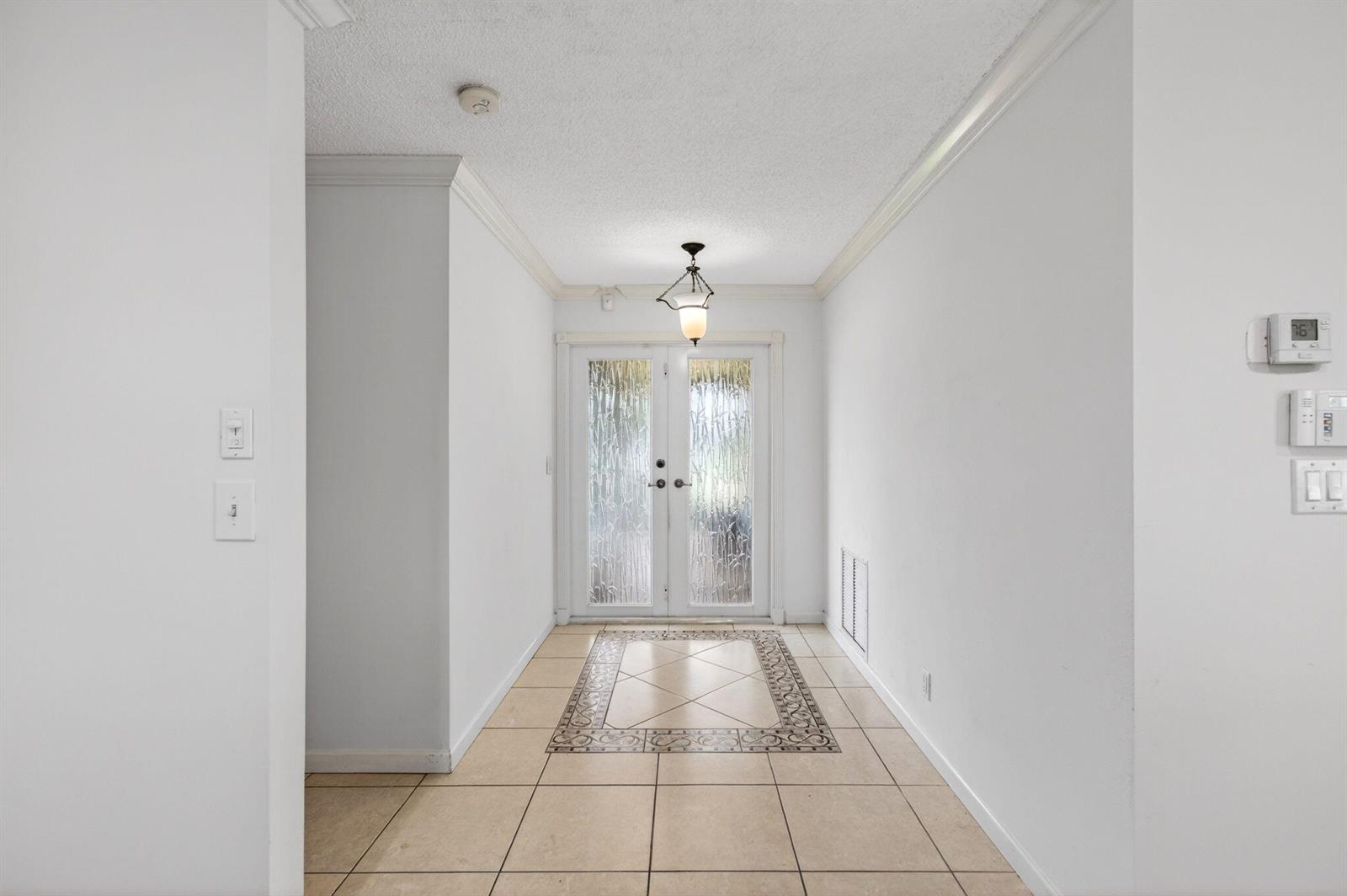 An entryway features white walls, a tiled floor with a decorative inlay, and double doors — 6049 Dusenburg Road, Delray Beach FL 33484, DELRAY BEACH, FL