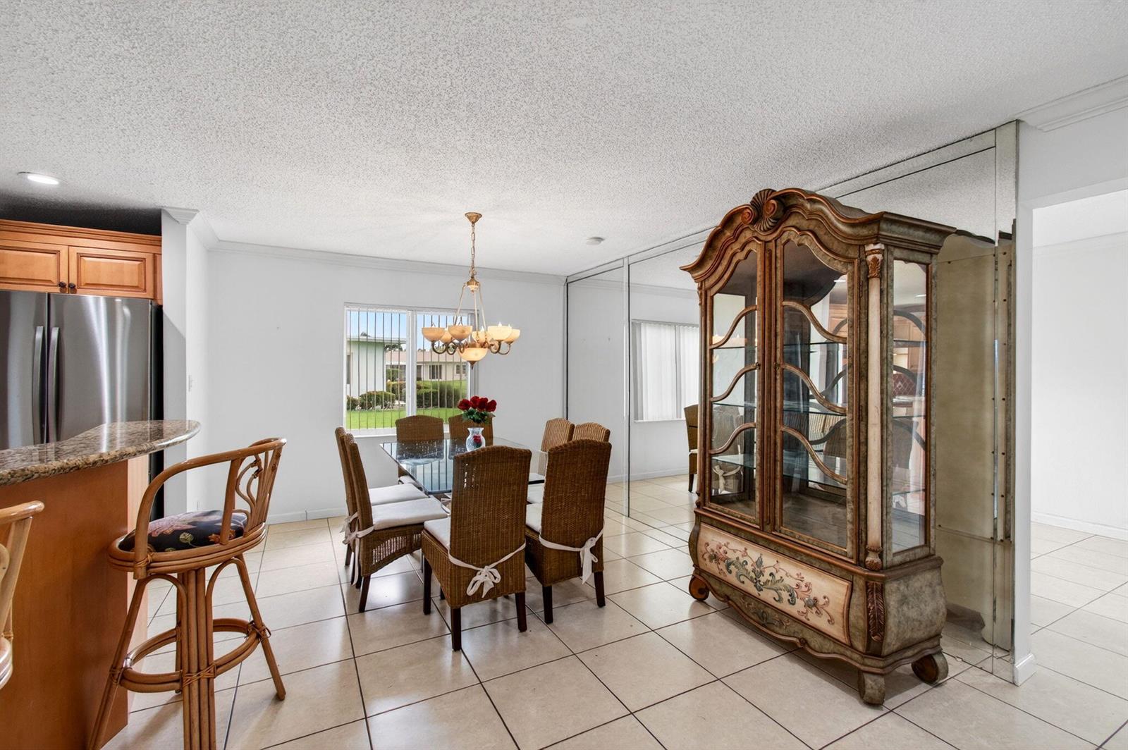 A dining area features a wicker chair set, a glass table, and a large mirrored wall — 6049 Dusenburg Road, Delray Beach FL 33484, DELRAY BEACH, FL