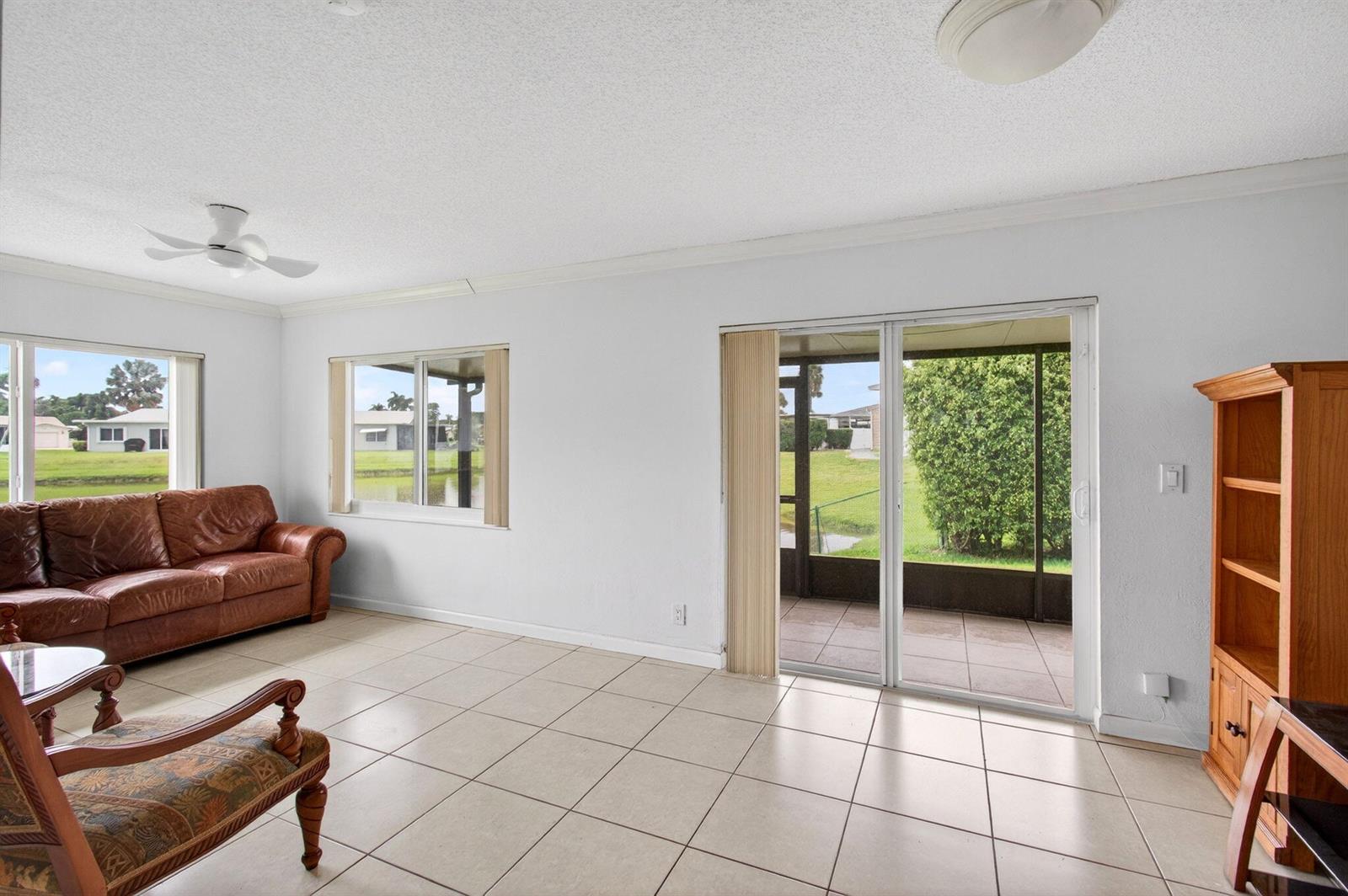 A living room with tile floors, a leather sofa, and sliding doors leading to a patio — 6049 Dusenburg Road, Delray Beach FL 33484, DELRAY BEACH, FL