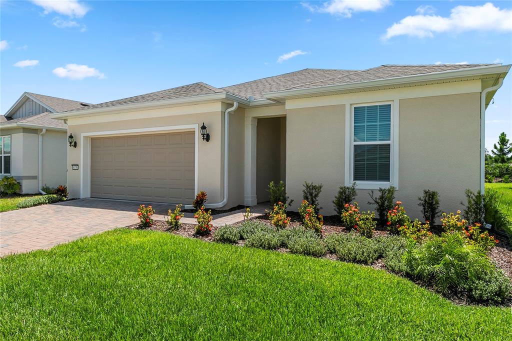 A single-story suburban house with a tan stucco exterior, a two-car garage, and landscaped yard — 6376 SHIMMERING SHORES LANE, ST CLOUD, FL