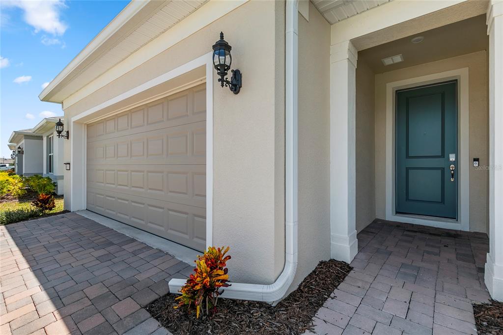A beige house exterior features a tan garage door, a teal front door, and pavers — 6376 SHIMMERING SHORES LANE, ST CLOUD, FL