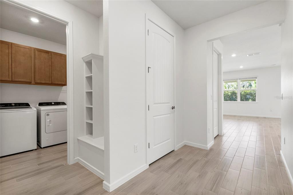 A laundry room with white appliances and wood-look tile flooring leads into an adjacent room — 6376 SHIMMERING SHORES LANE, ST CLOUD, FL