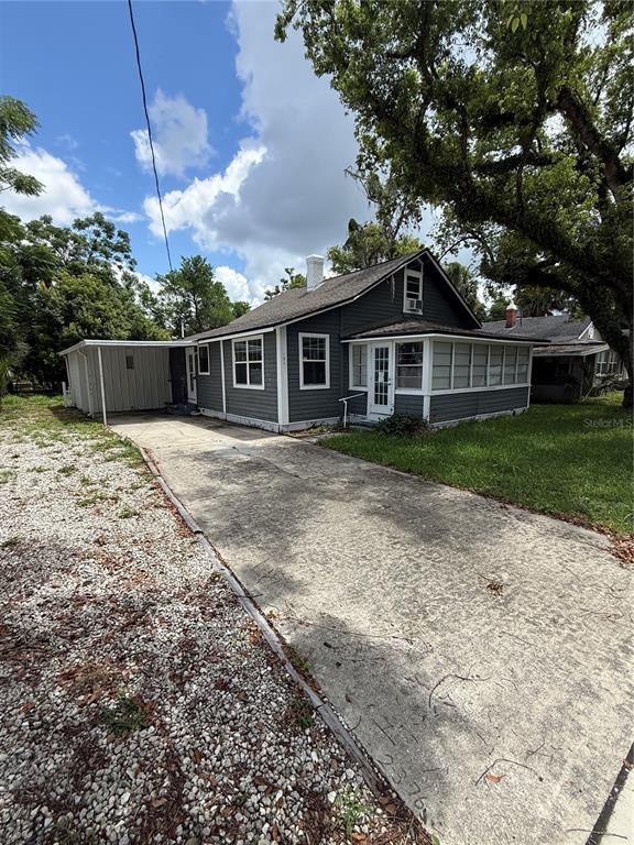 A gray house with a white-trimmed porch and a concrete driveway sits under large trees — 137 E MAINE AVENUE, LONGWOOD, FL