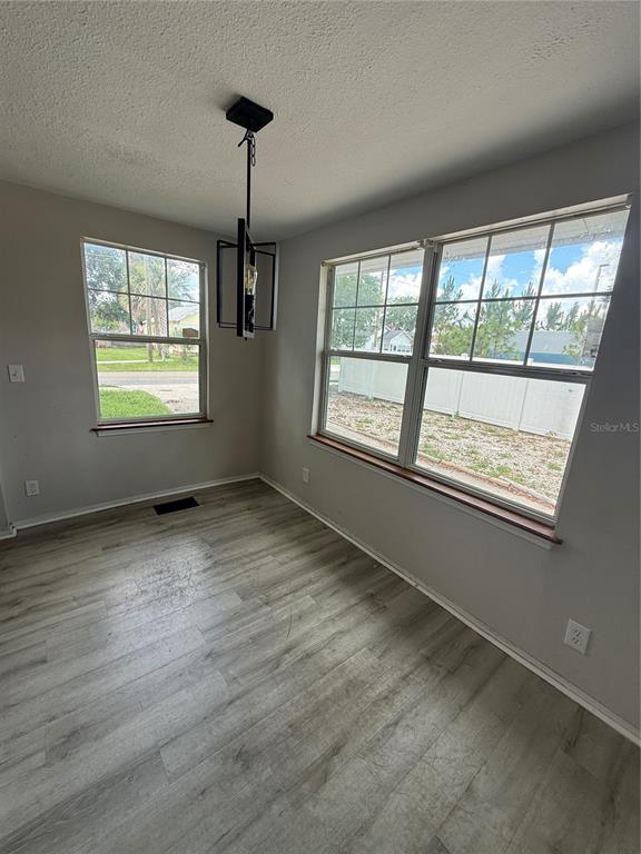 A dining area with light wood-look flooring, gray walls, a pendant light, and two windows — 137 E MAINE AVENUE, LONGWOOD, FL