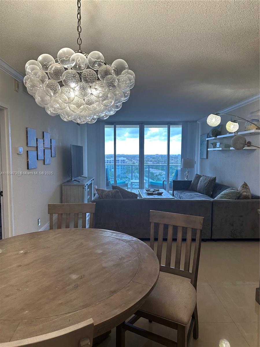 A dining area with a round wooden table overlooks a living room with a balcony view — 2501 S Ocean Dr # 1228, Hollywood FL 33019, HOLLYWOOD, FL