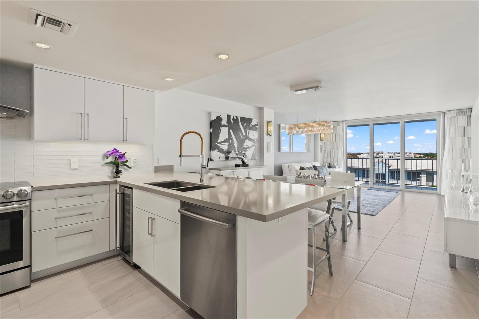 A modern kitchen with white cabinets, a quartz island, and an open view of a balcony — 800 SE 20th Avenue # 809, Deerfield Beach FL 33441, DEERFIELD BEACH, FL
