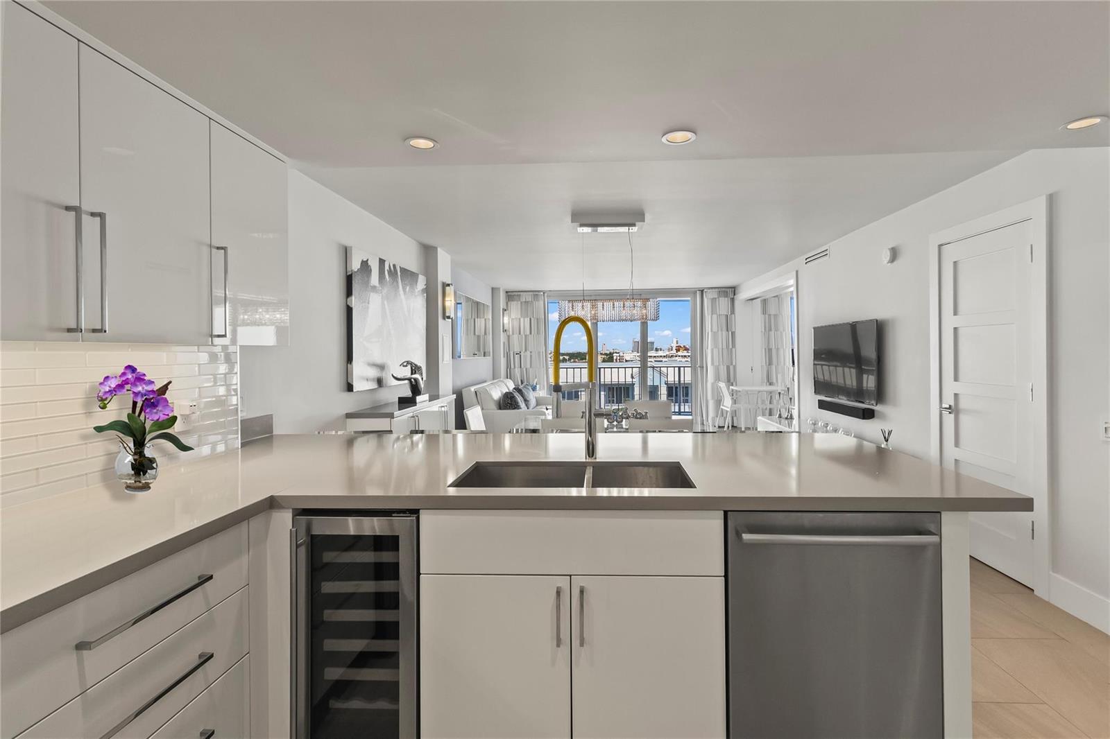 A modern kitchen with white cabinets, quartz countertops, and a view of the balcony — 800 SE 20th Avenue # 809, Deerfield Beach FL 33441, DEERFIELD BEACH, FL